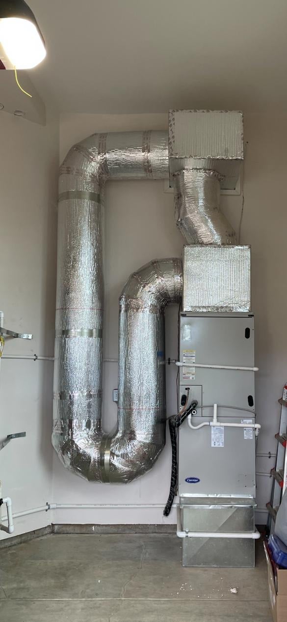 Carrier air handler and insulated ductwork installed in a residential garage.