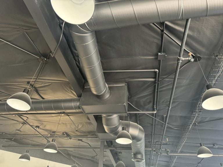 Spiral ductwork and plenum installed in a commercial ceiling.