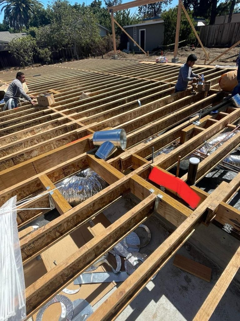 Subfloor ductwork being installed between floor joists during construction.